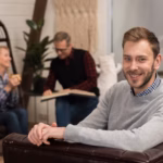 smiley-man-posing-sofa-with-defocused-parents_23-2148414910