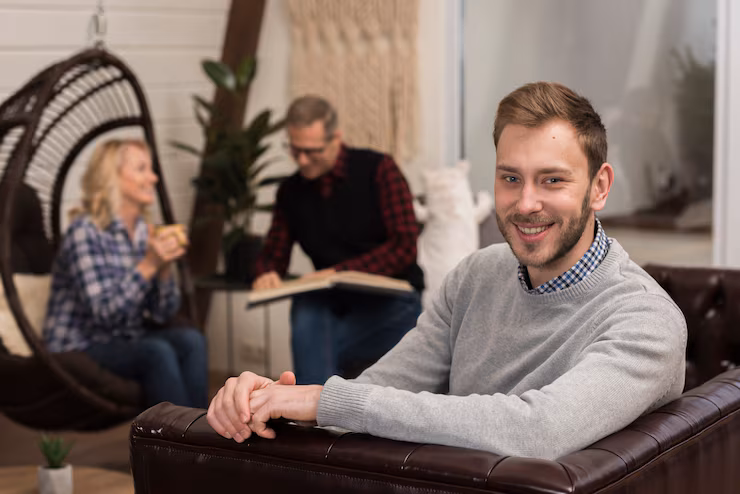 smiley-man-posing-sofa-with-defocused-parents_23-2148414910